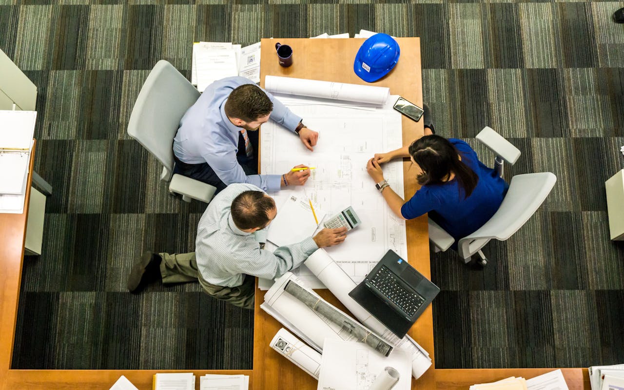 creative Top view of a team working on construction plans in an office setting.